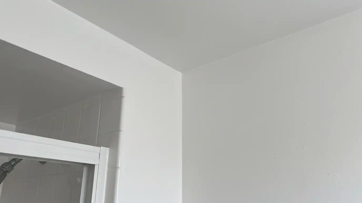 After: Water damage repaired beside a shower | Music City Shower Service After: a bathroom wall and ceiling with a repaired, smooth, freshly painted wall and ceiling with clean tile