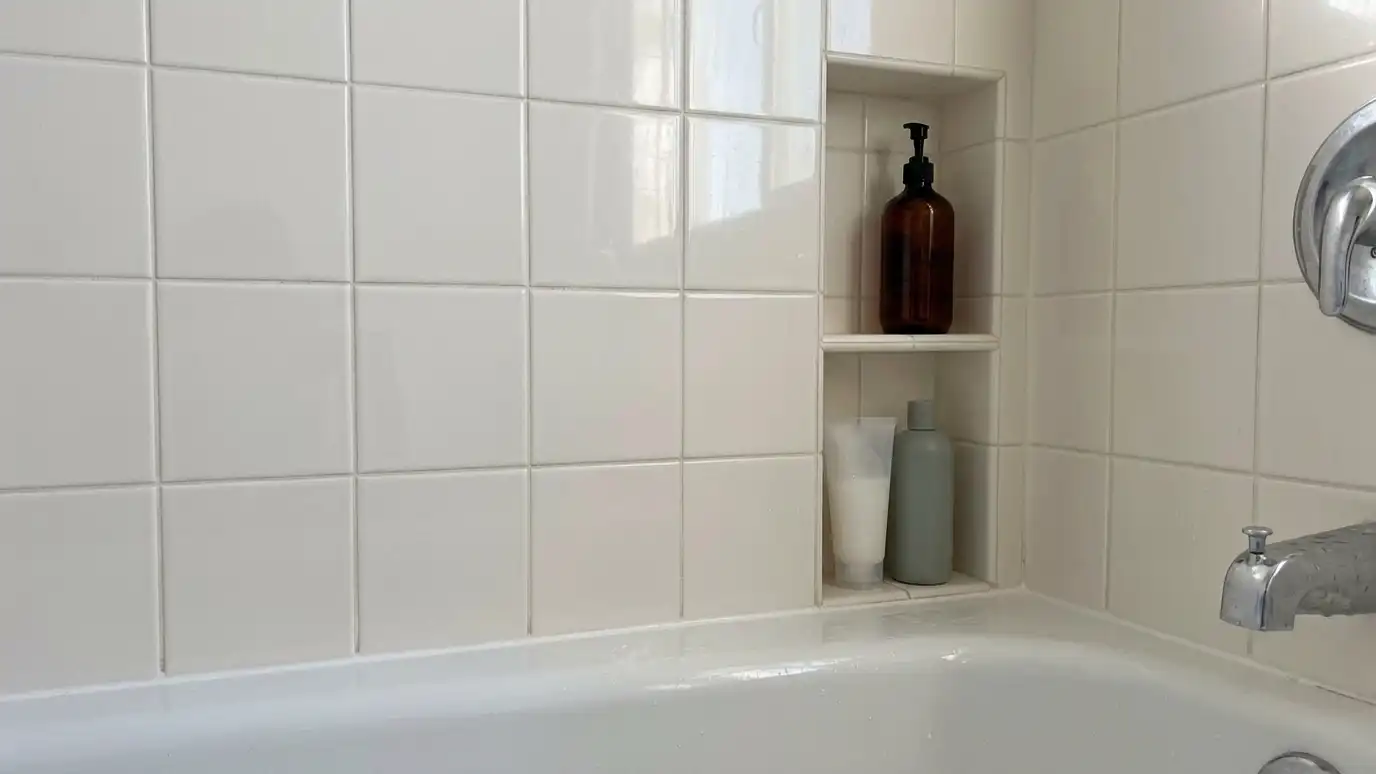 After: Crowded bottles given a built-in niche | Music City Shower Service After: a shower wall with a recessed tiled niche with the bottles neatly arranged