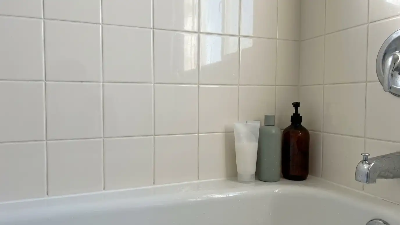 Before: a shower wall with a flat wall with bottles crowded on the tub edge