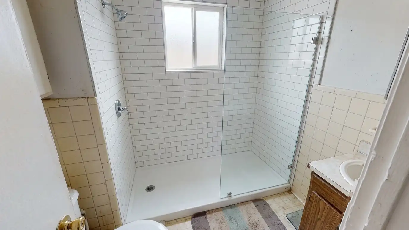 After: A tired tub turned into a walk-in shower | Music City Shower Service After: a small bathroom with a sleek walk-in shower with white subway tile and clear glass