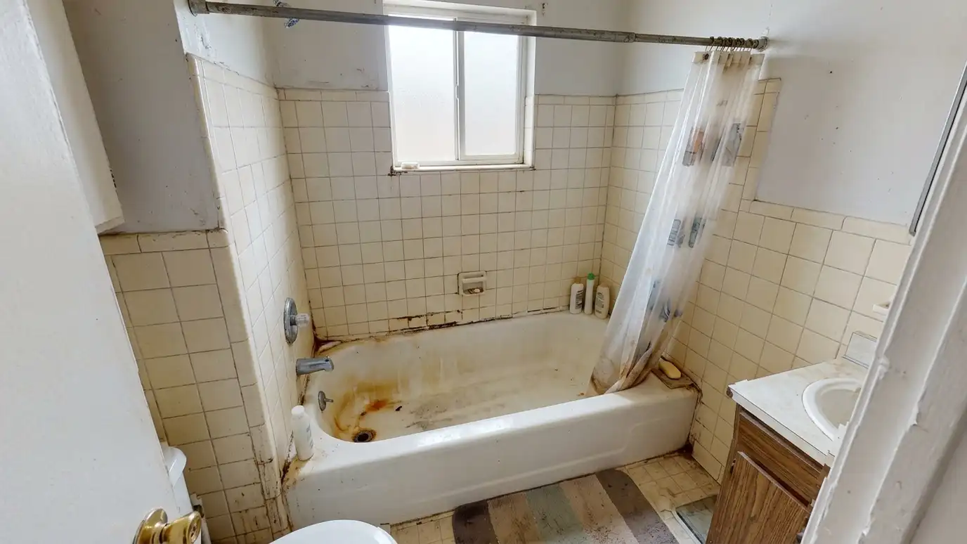 Before: a small bathroom with an old stained tub with a plastic curtain