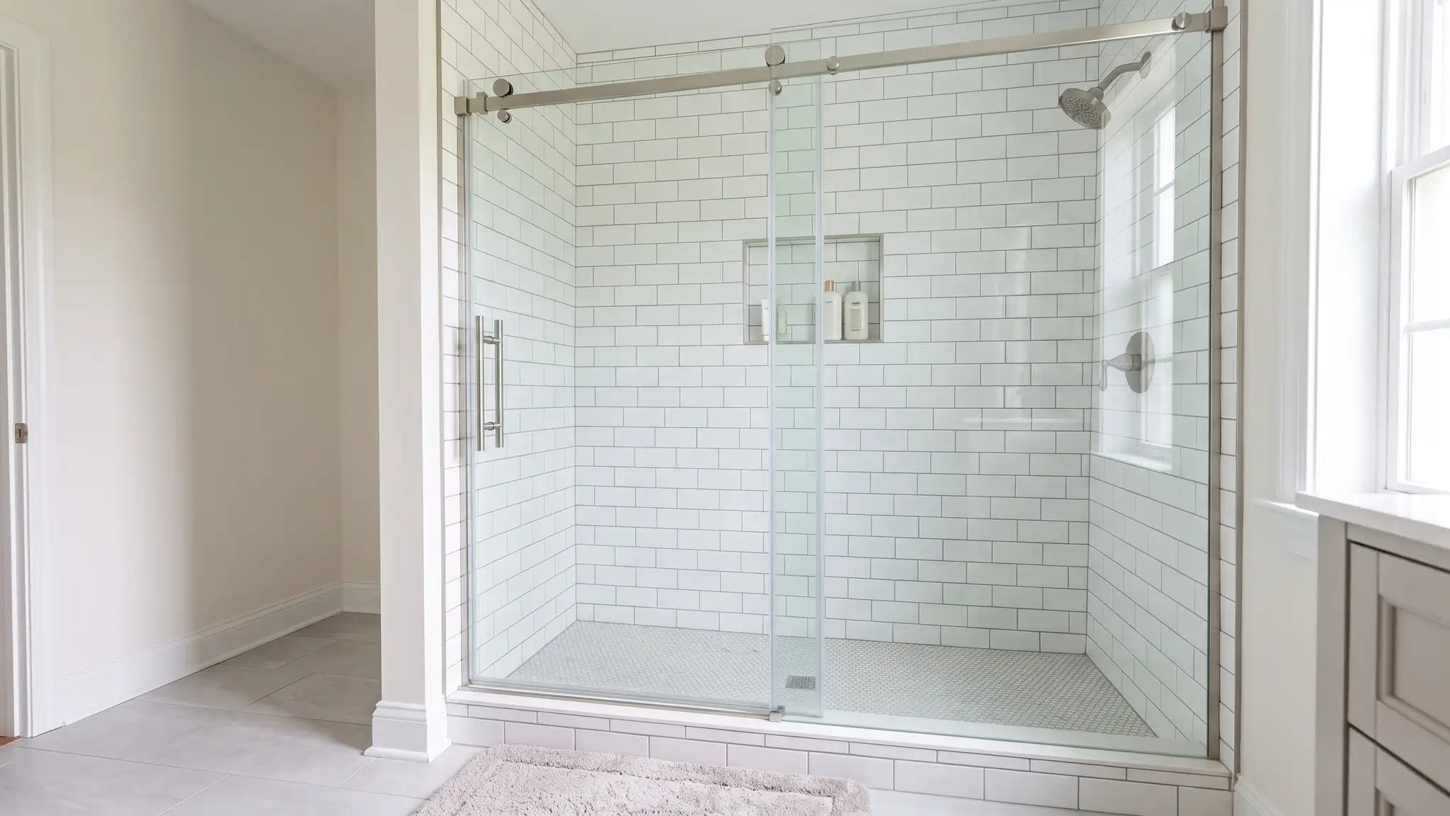 Shower Replacement and Installation | Music City Shower Service Sliding glass doors on a bright shower stall tiled in white subway tile with a built-in niche and chrome fixtures